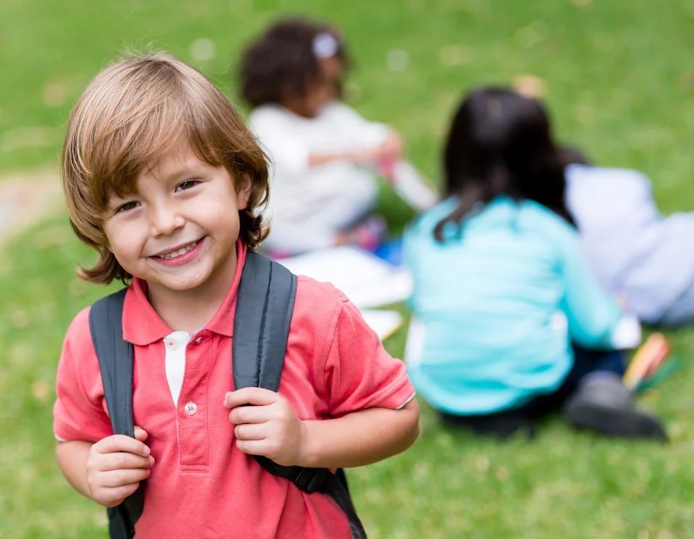 Happy school boy holding his bag and smiling